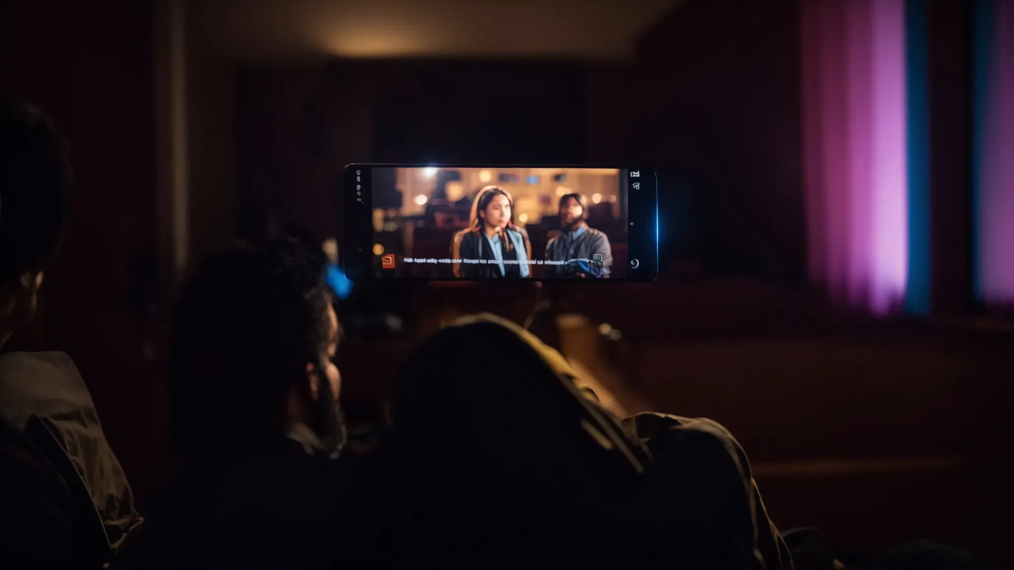 a viewer sits engulfed in the glow of a movie on a screen, a smartphone beside them displaying a review.