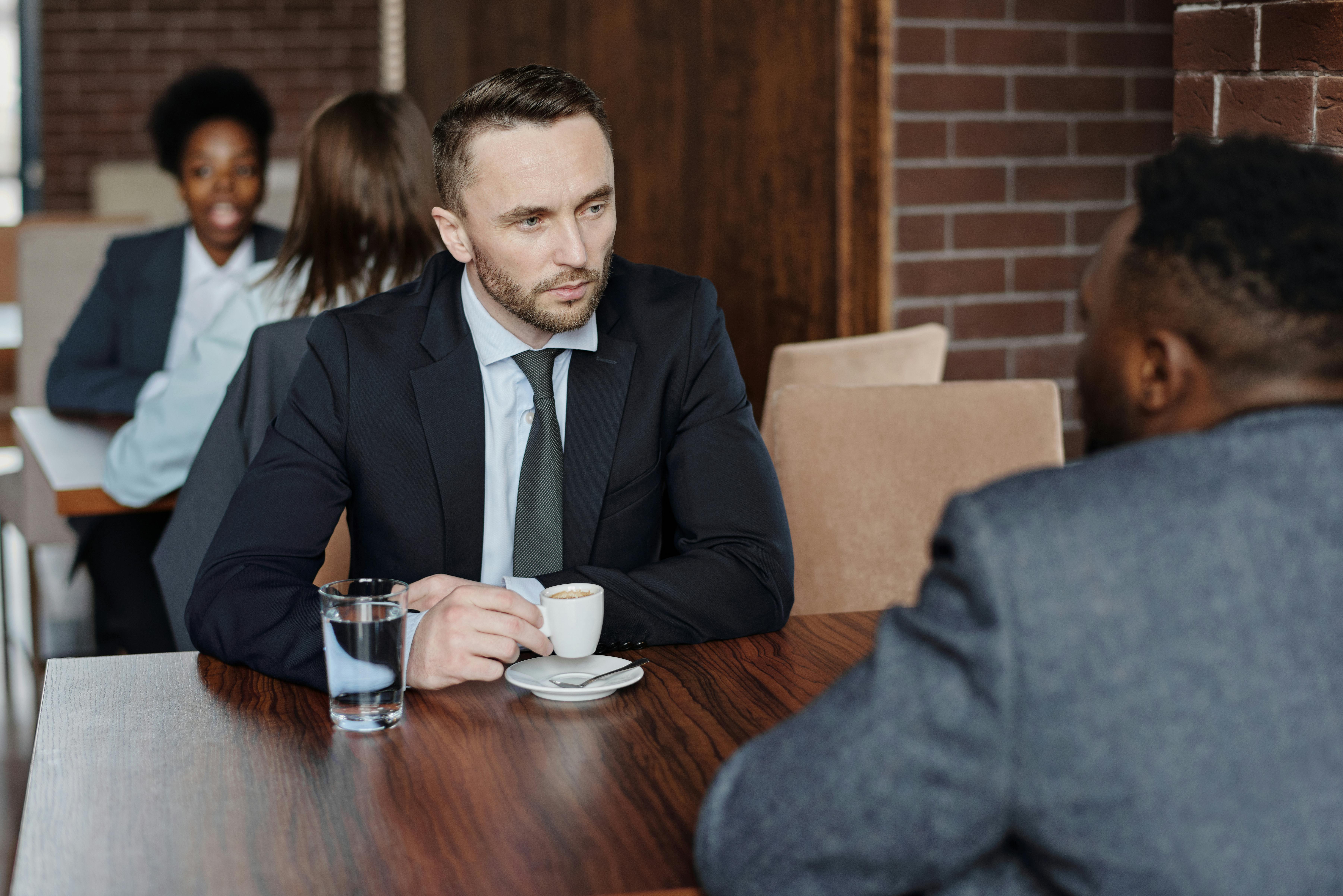 a producer and an actor sitting across from each other at a negotiation table, in a calm, well-lit office.