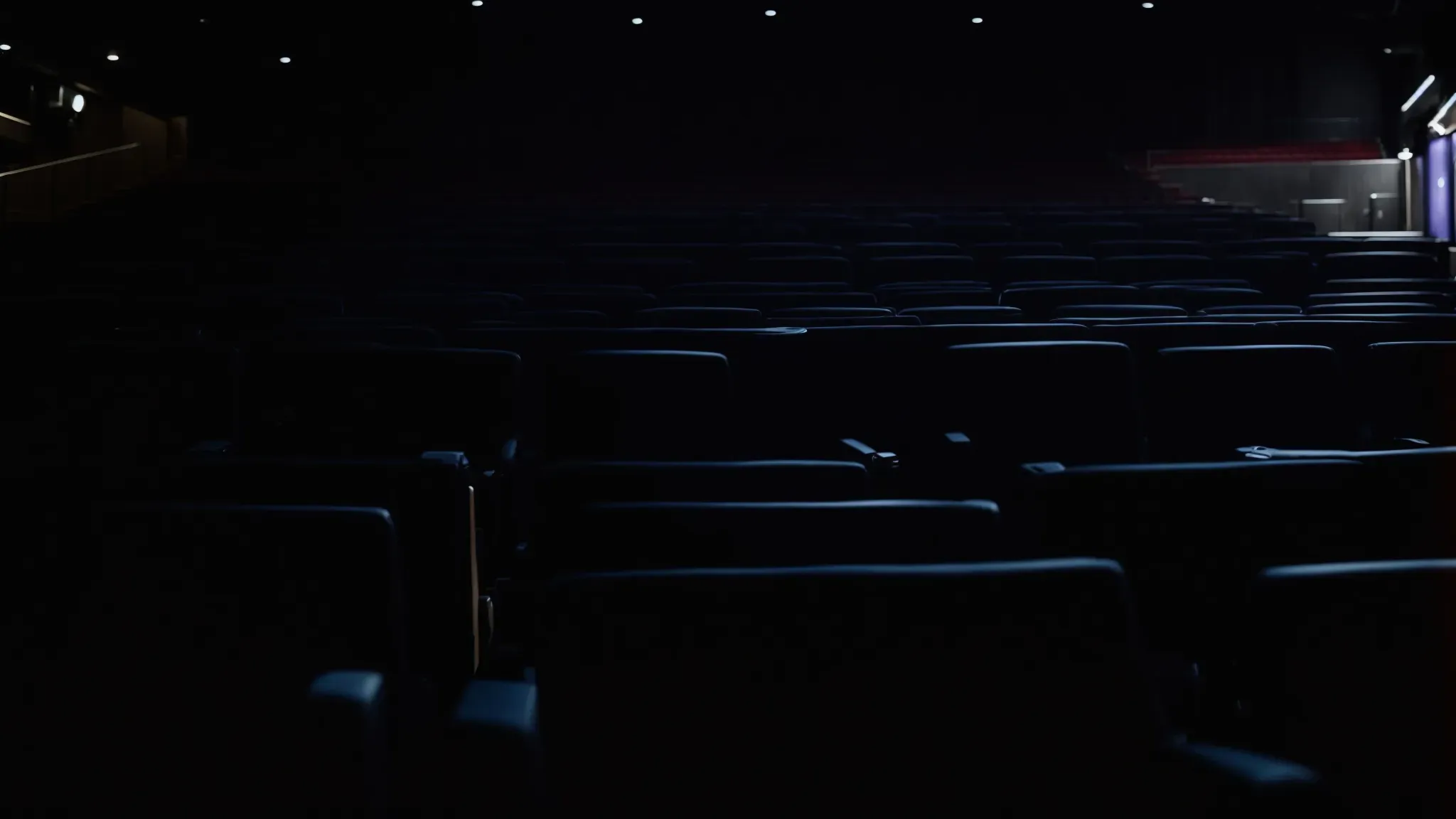 a darkened movie theater with an empty screen, hinting at anticipation for something more.