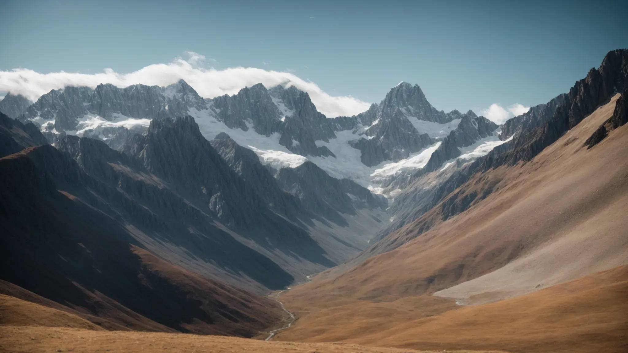 a wide panoramic view of a majestic mountain range under a clear sky, accentuating the vastness and isolation of the landscape.