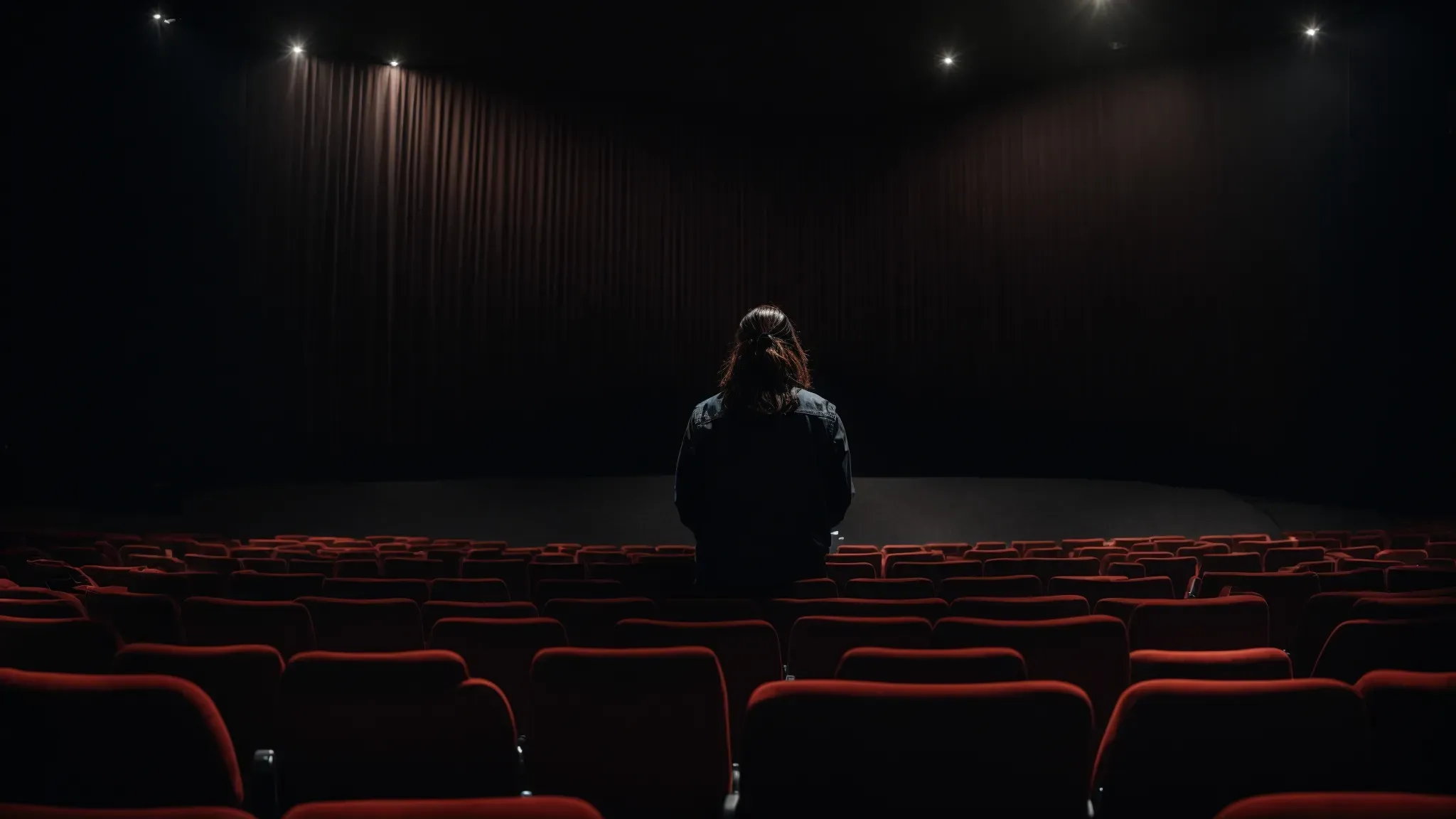 a moviegoer sits immersed in a dark, state-of-the-art theater, with speakers arranged to create an enveloping audio experience.