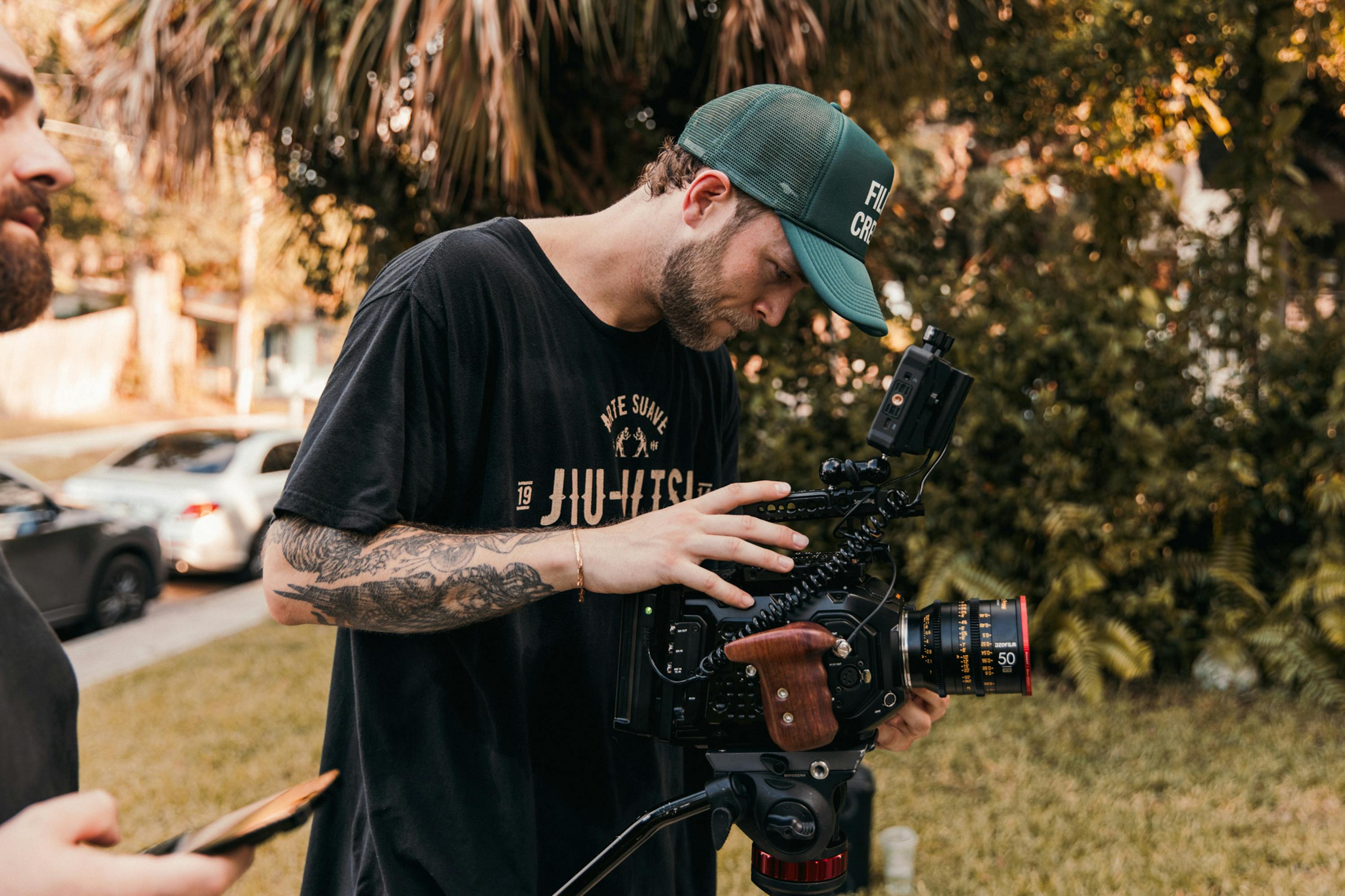 a film producer operating a camera captures an interview subject against the backdrop of a bustling street market.