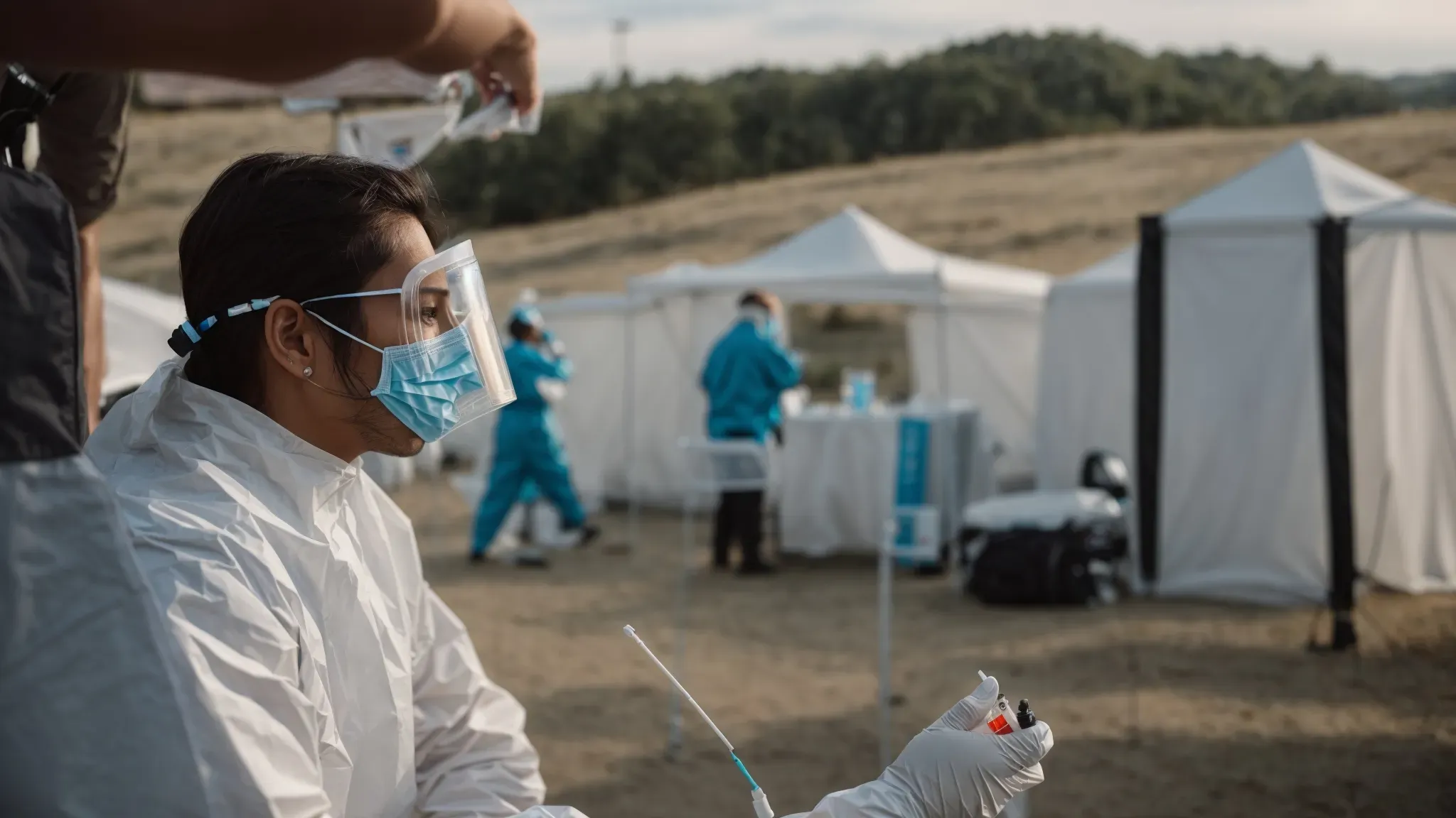 a clinical professional in protective gear administers a covid-19 nasal swab test to a film crew member in an outdoor, makeshift testing station.