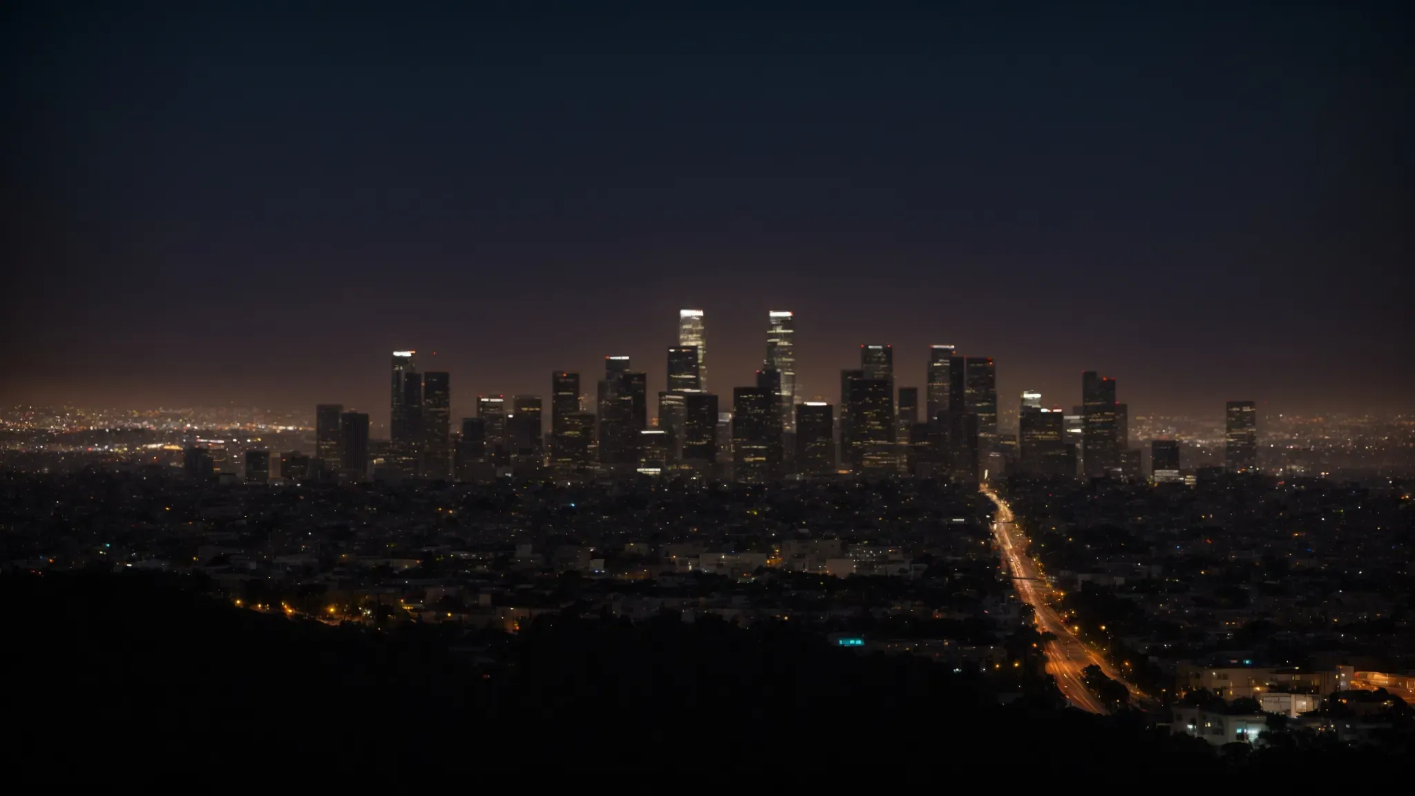 a skyline view of los angeles at dusk, showcasing the glow of studio lights among city buildings.