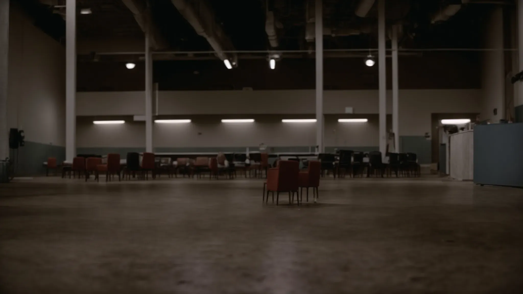 a dimly lit, empty union hall floor scattered with chairs, suggesting a hastily abandoned meeting.