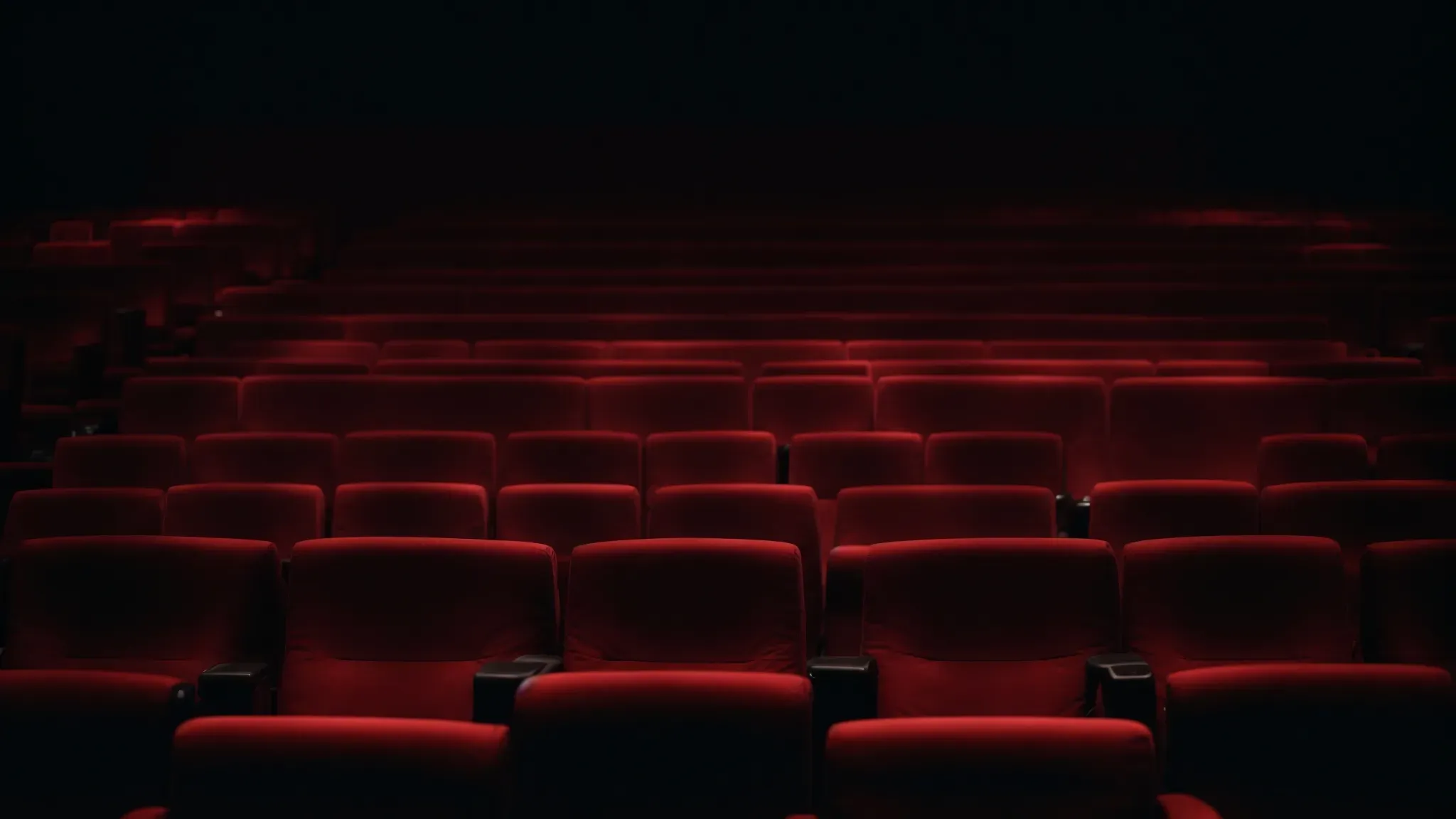 a half-filled cinema with the mysterious glow of a single screen illuminating an otherwise dark room.