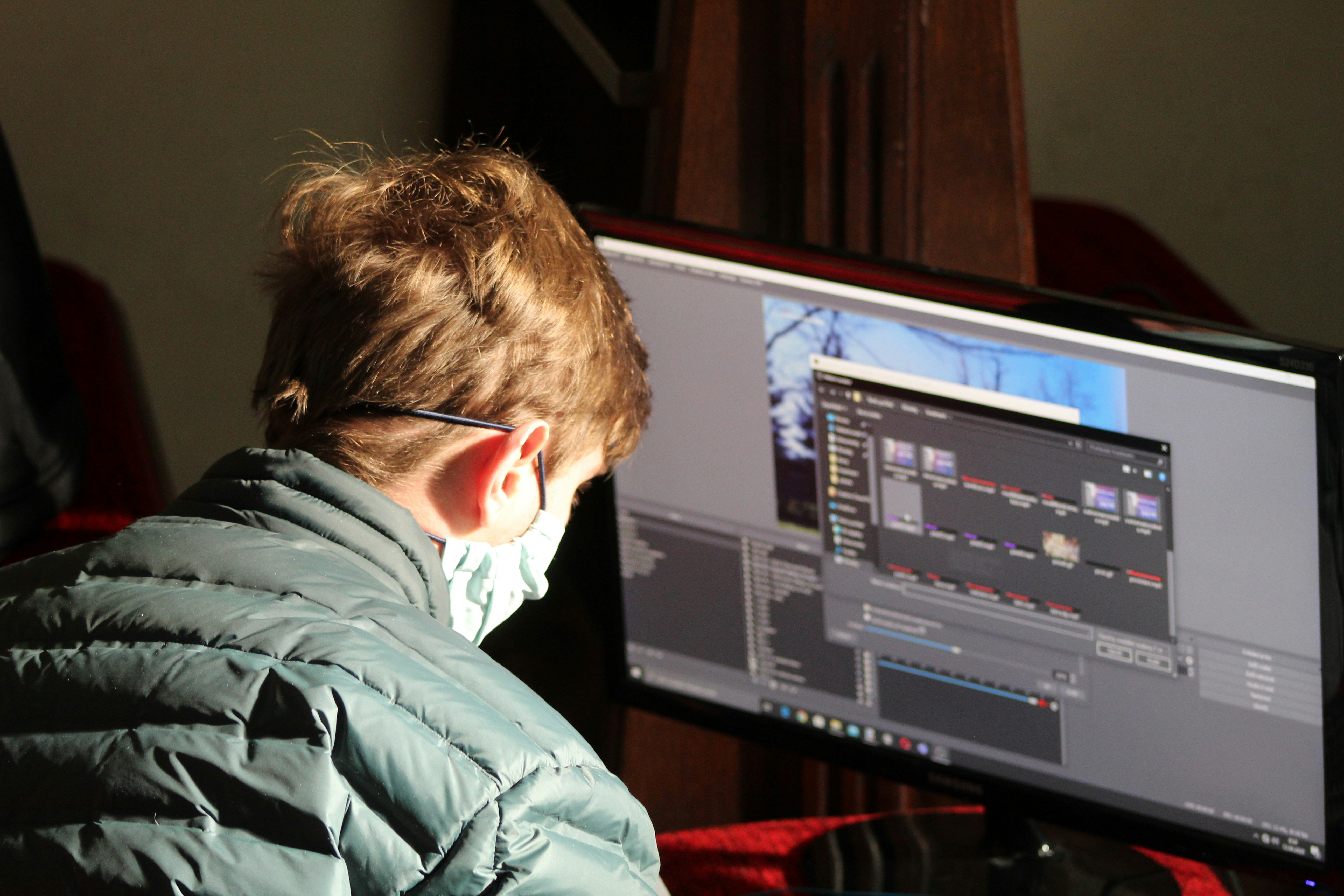 a film editor and director intently review footage on large screens in a dimly lit editing studio. Explore Saturation.io