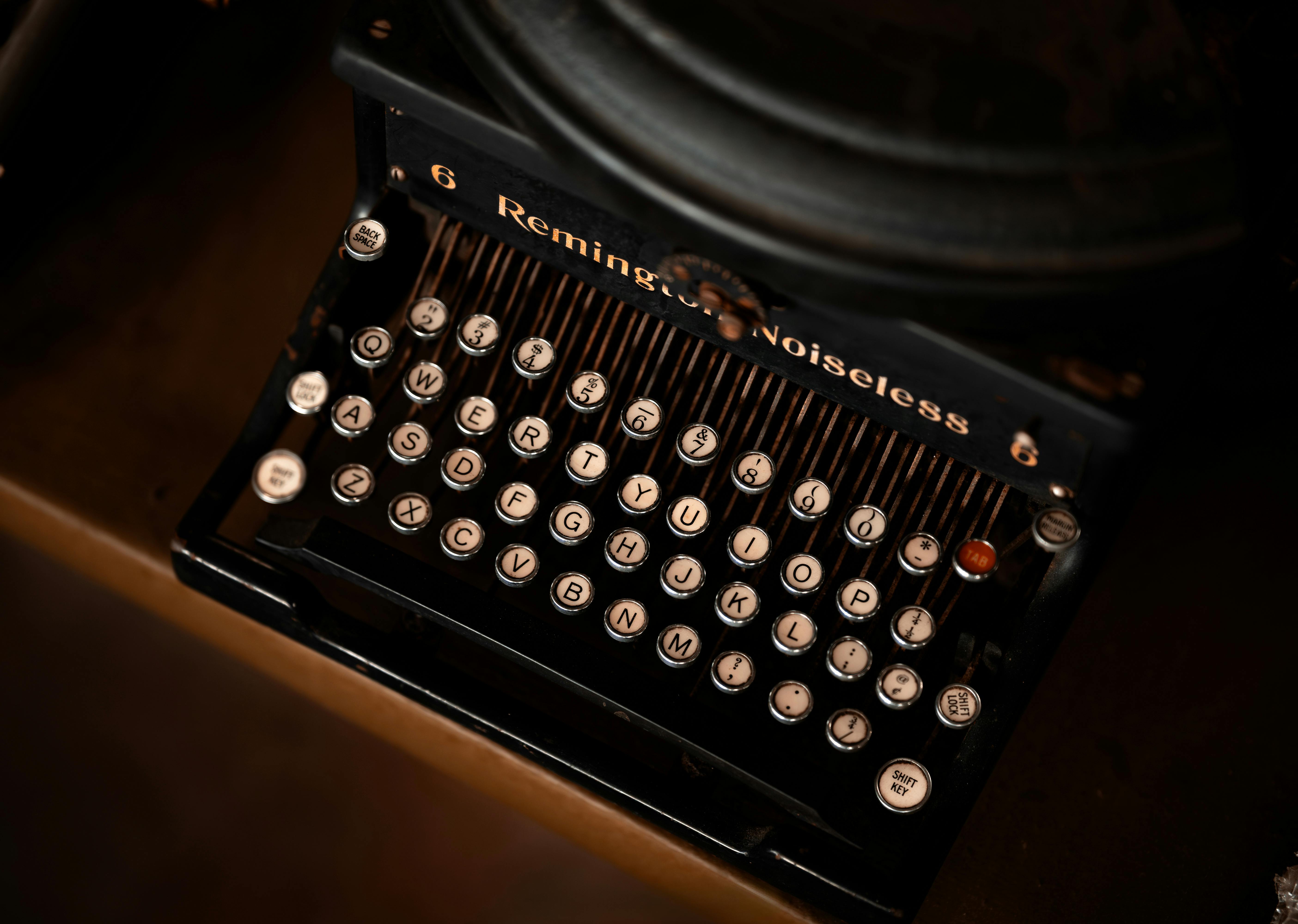 a typewriter sits on a vintage wooden desk littered with annotated script pages.
