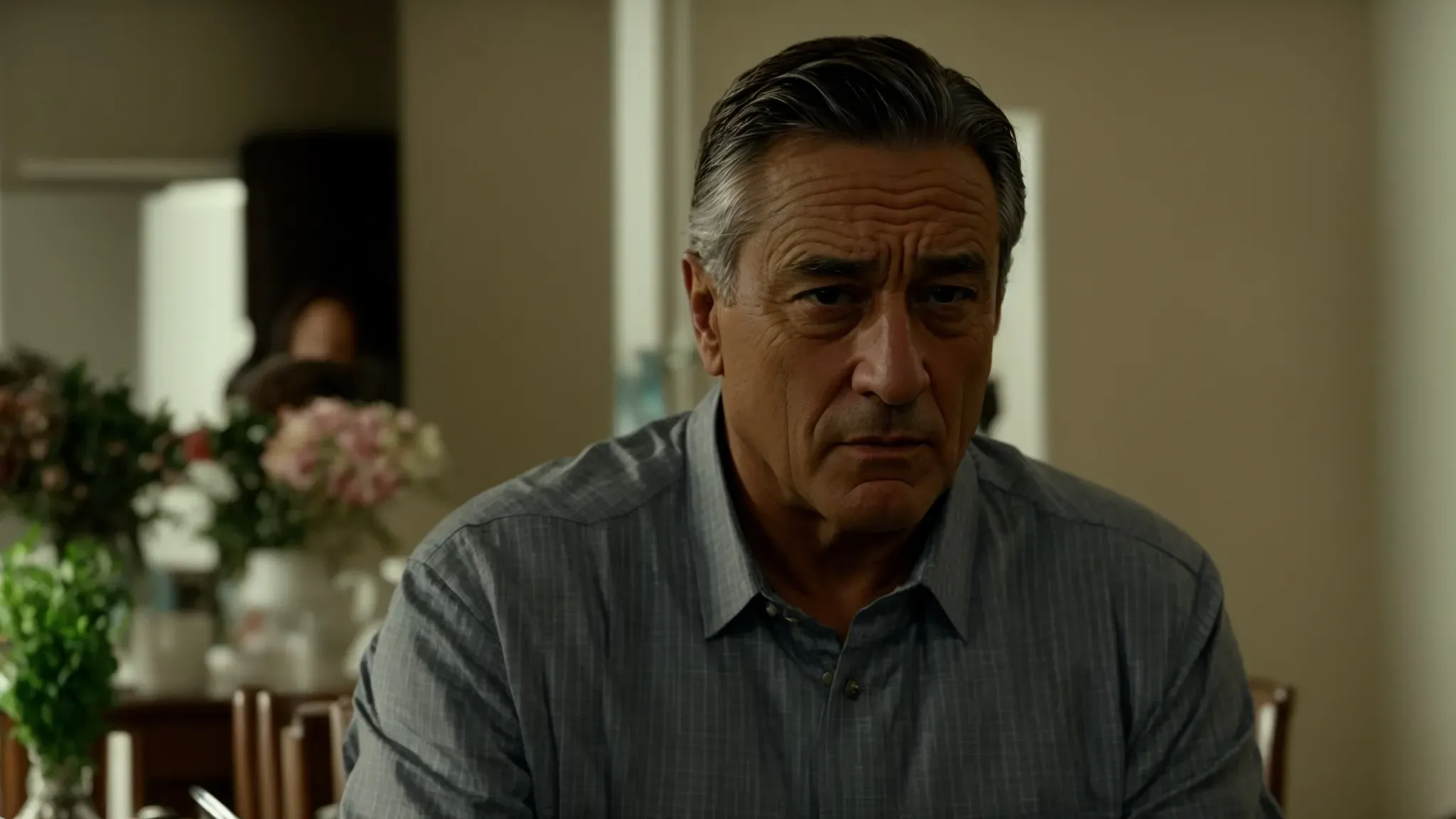 robert de niro sitting at the dinner table with an expression of concern during a family scene in 