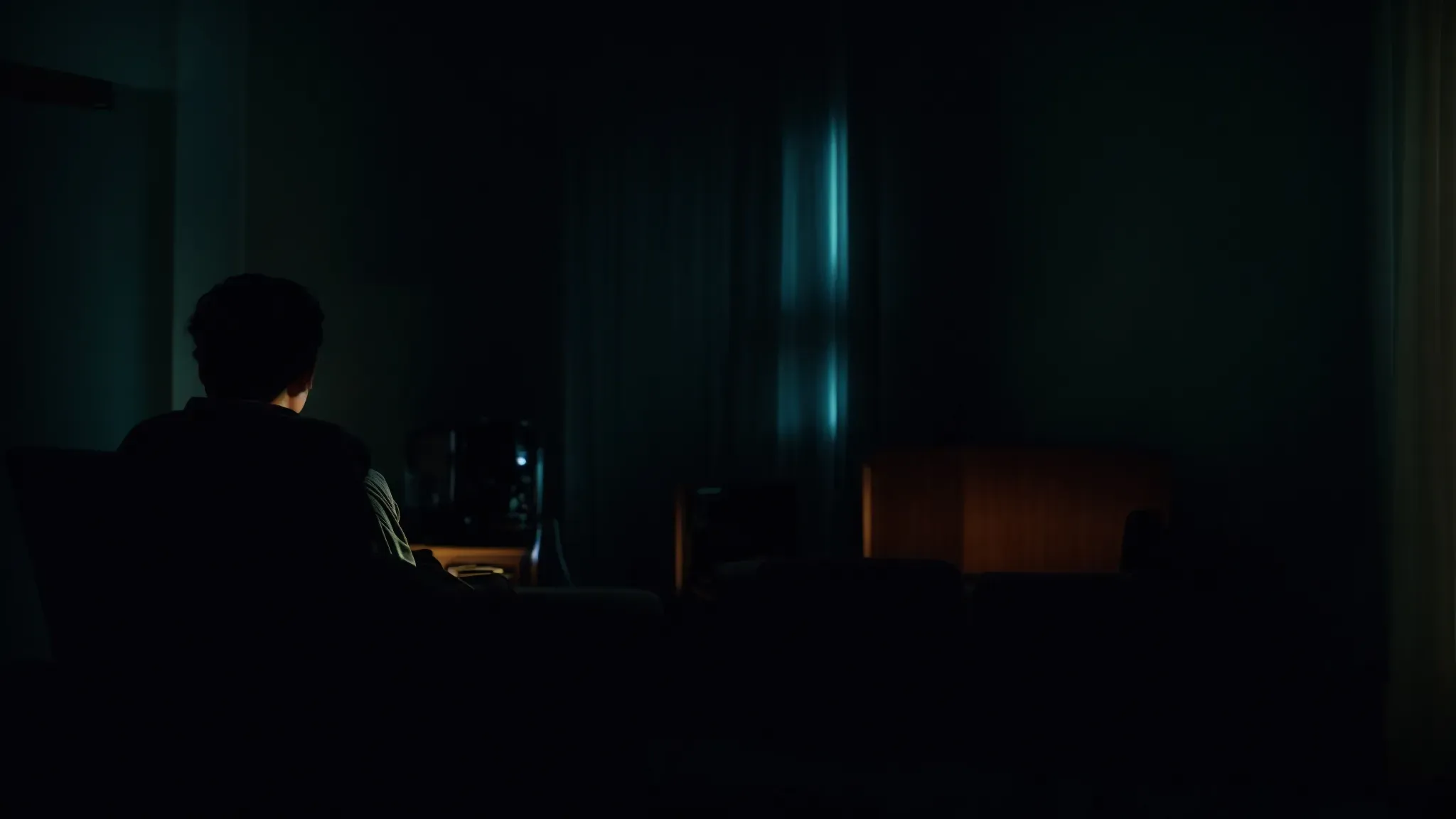 a dimly lit living room where a person sits alone, eyes wide in both horror and fascination, as shadows dance across their face from the flickering light of a television screen showing an unidentifiable grotesque transformation.