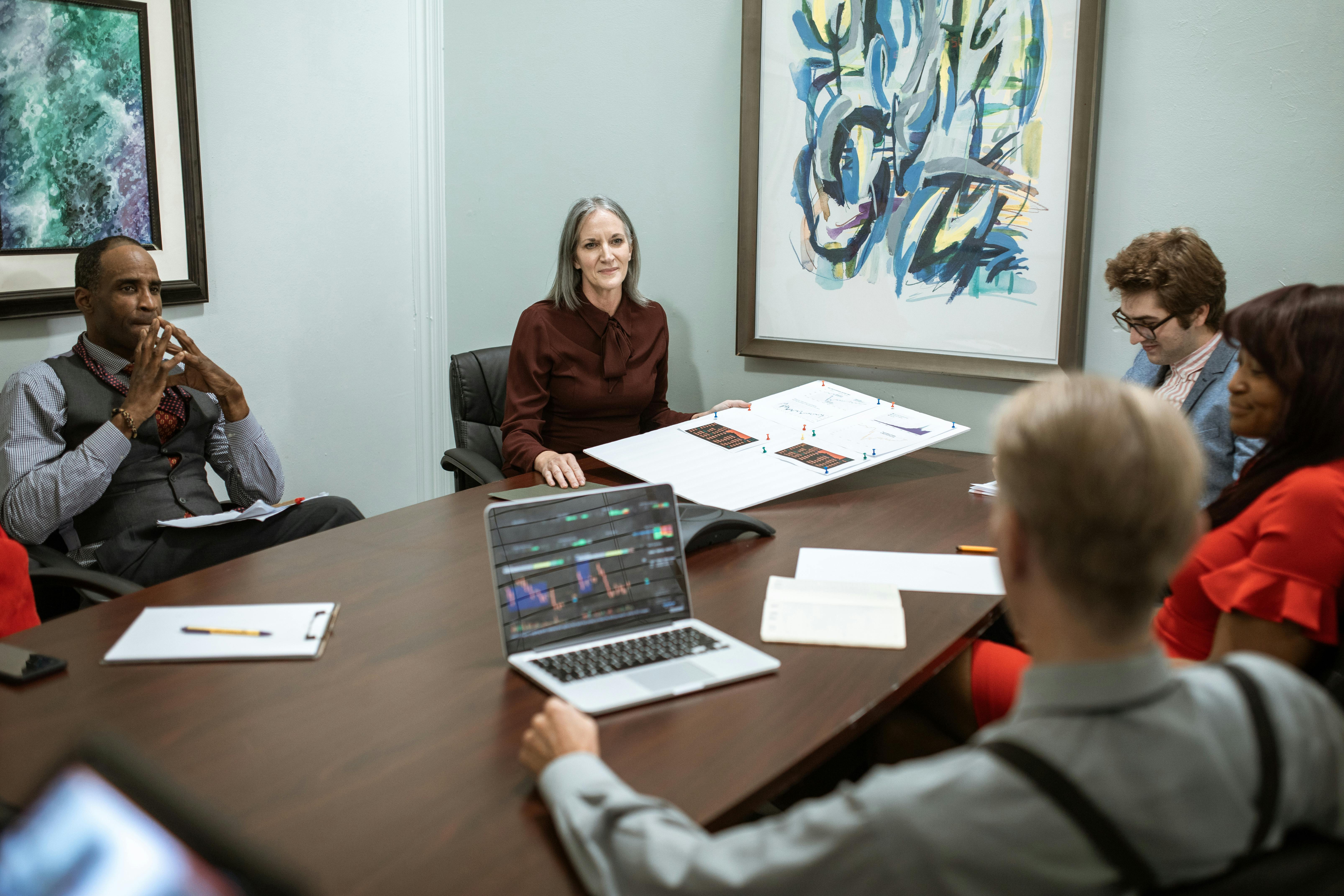 a roundtable discussion among film industry professionals, with laptops and digital devices visible, set in a modern conference room.