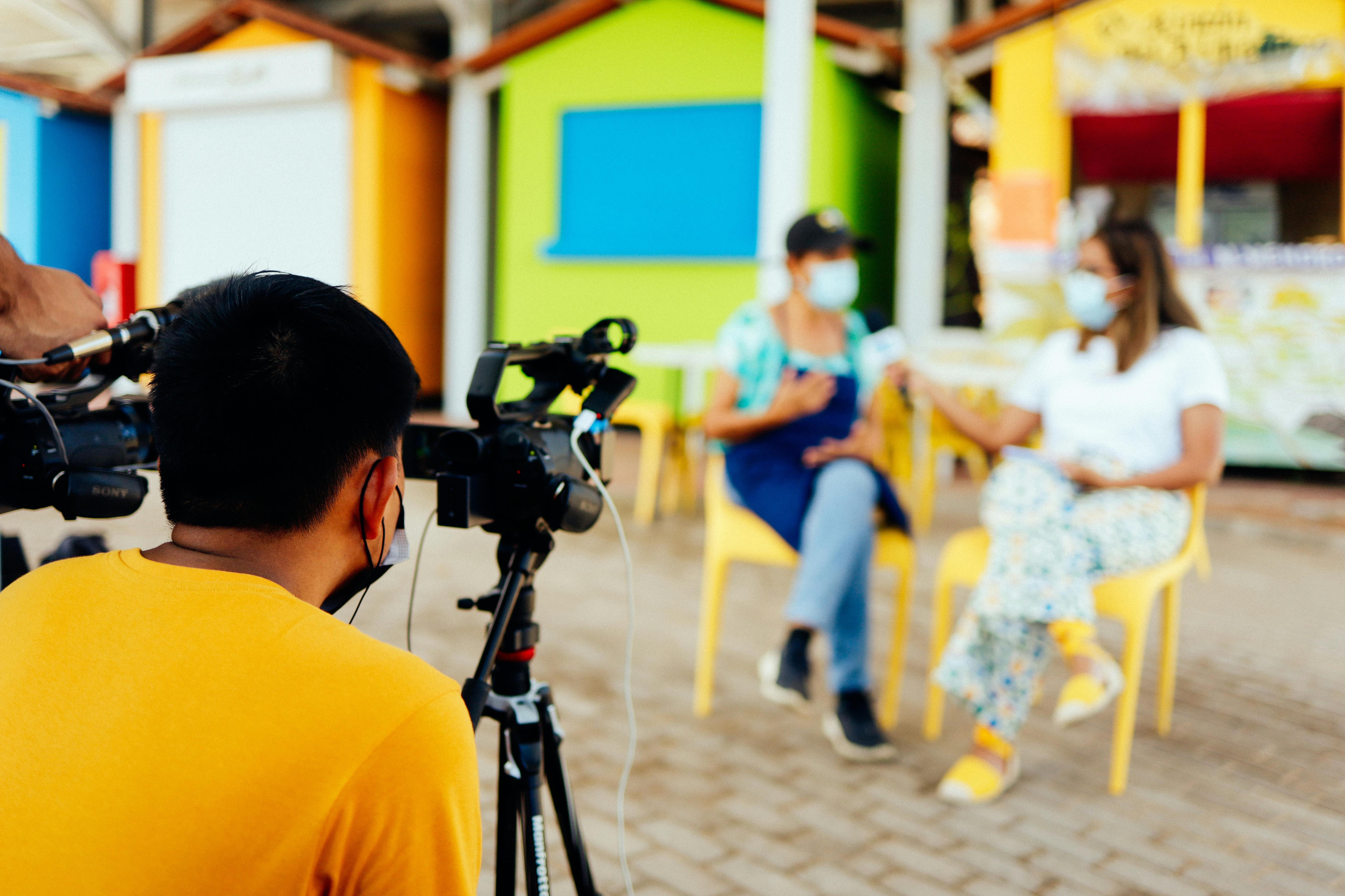 a group of eager filmmakers gathered around a screen, discussing their latest project in a cozy, dimly-lit room filled with filmmaking equipment.
